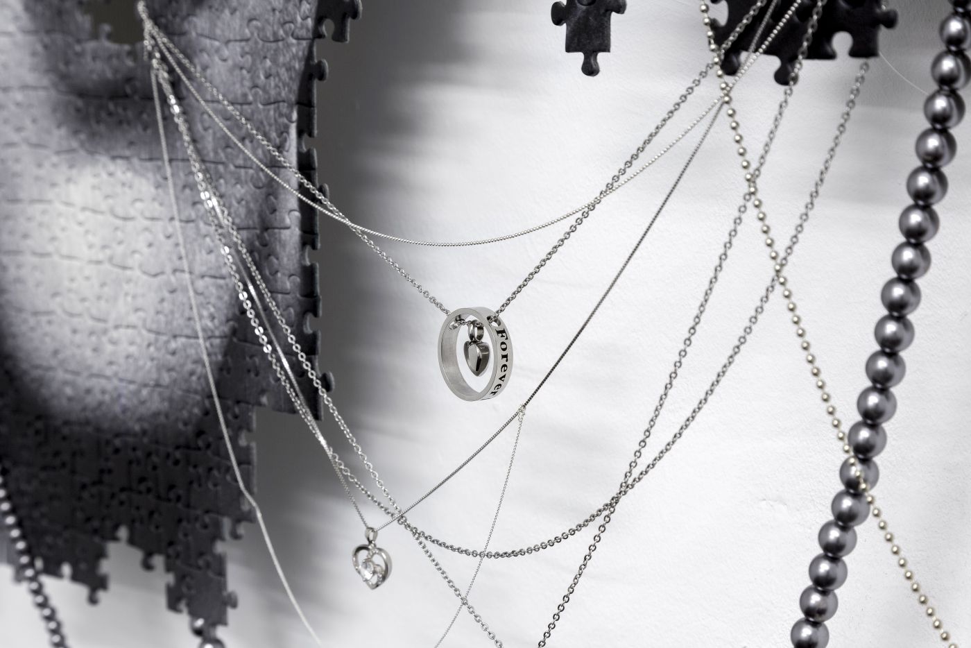 Julian-Jakob Kneer, EROS / THANATOS (YOU DID IT, FOREVER YOUNG), 2021, Digital print on puzzle, silver and steel chains, engraved silver and steel lockets, plastic coated jewelry, aluminium construction, 105cm x 90cm x 7cm, (detail)